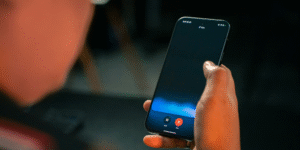 A person holding a smartphone and interacting with the screen, which appears to be a camera or live video interface.