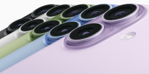 A close-up, diagonal shot of multiple iPhone 17 cameras in various colors: black, white, green, light blue, and lavender, emphasizing the dual-lens design