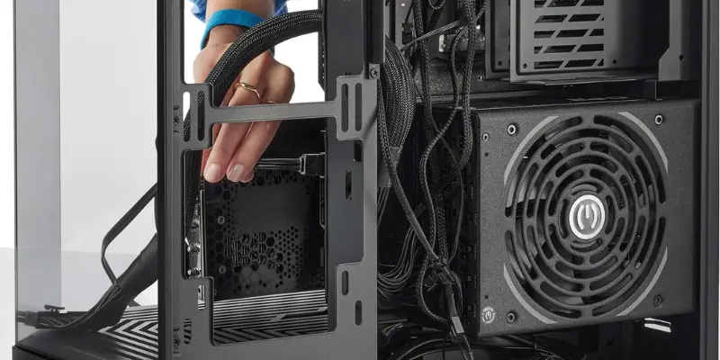 A Close Up View Inside A Pc Case Showing A Hand Installing A Graphics Card Gpu Into The Vertical Mounting Bracket Near The Front Of The Case With A Power Supply Unit Psu And Cables Visible In The Backg