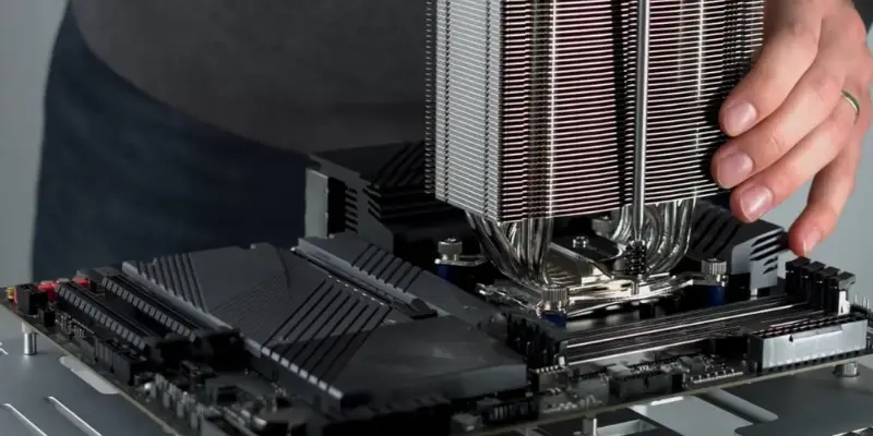 A Hand Lowering A Large Silver Tower Style Cpu Air Cooler Onto The Mounting Bracket Installed On The Motherboard Preparing To Secure It Over The Cpu